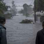 Rua alagada e moradores observando os efeitos de uma tempestade em município do Rio Grande do Sul