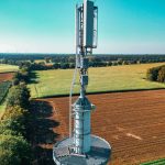 Vista aérea de uma torre de telefonia instalada entre áreas agrícolas.