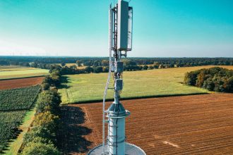 Vista aérea de uma torre de telefonia instalada entre áreas agrícolas.