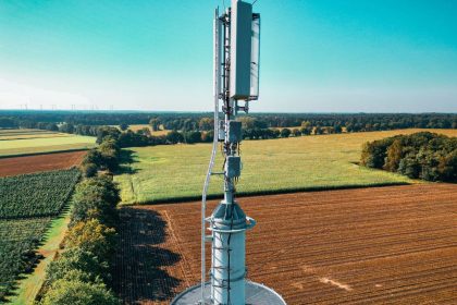 Vista aérea de uma torre de telefonia instalada entre áreas agrícolas.
