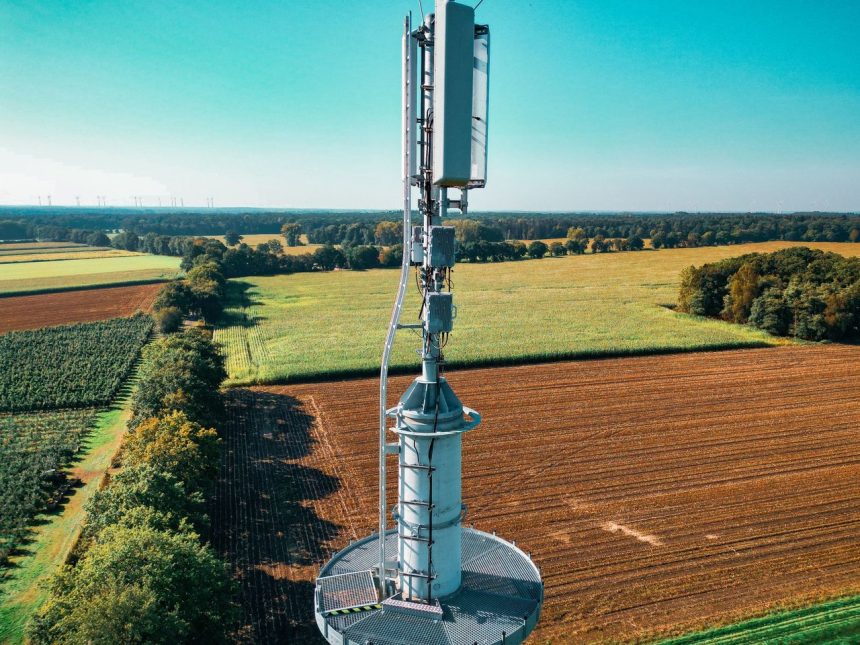 Vista aérea de uma torre de telefonia instalada entre áreas agrícolas.