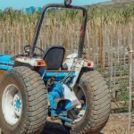 Trator azul estacionado em um campo agrícola durante o dia.