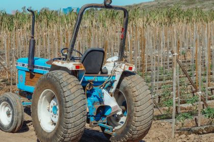 Trator azul estacionado em um campo agrícola durante o dia.