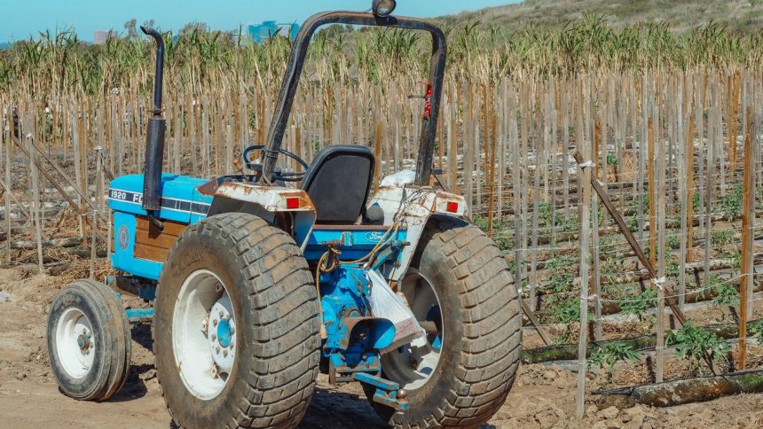 Trator azul estacionado em um campo agrícola durante o dia.